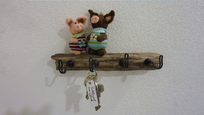 Zwei kuschelige Plüschtiere stehen auf einem Holzregal mit Schlüsselhaken.